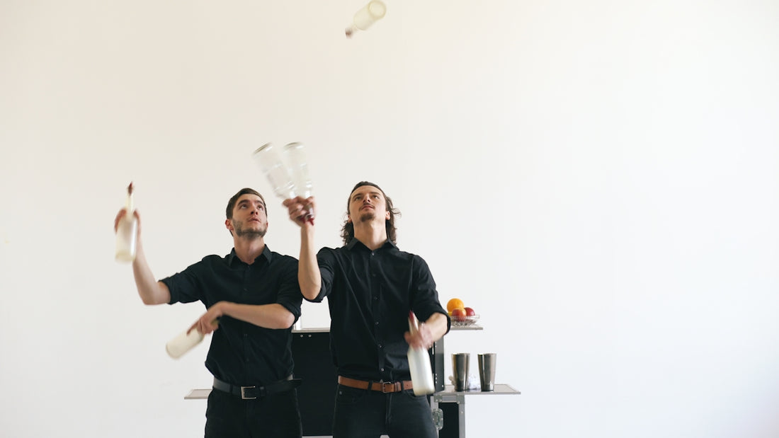 Two bartenders juggling bottles against a white background