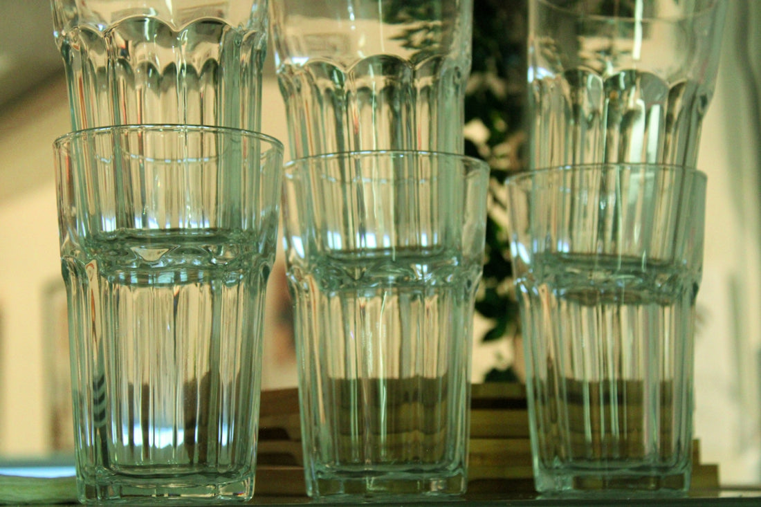 Stacked clear glass tumblers on a shelf.
